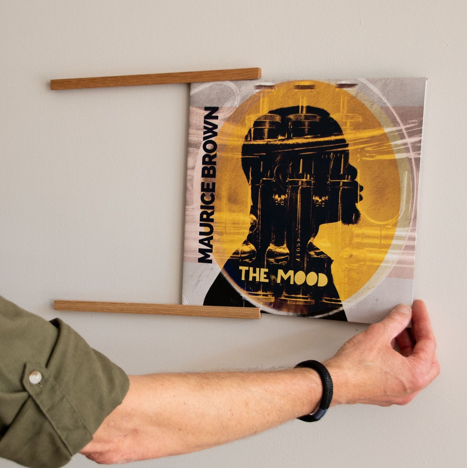 Platenliefhebber plaatst een lp-hoes in het eikenhouten Display SINGLE wandrek voor vinyl